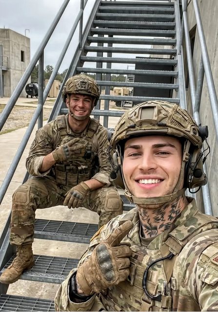 Two young men in full military camouflage uniforms and tactical gear smile for a selfie while sitting on metal stairs at an outdoor facility.