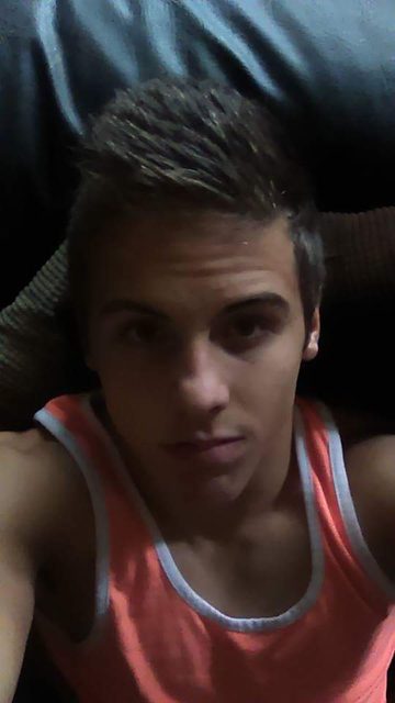 A young man takes a selfie in a sporty tank top.