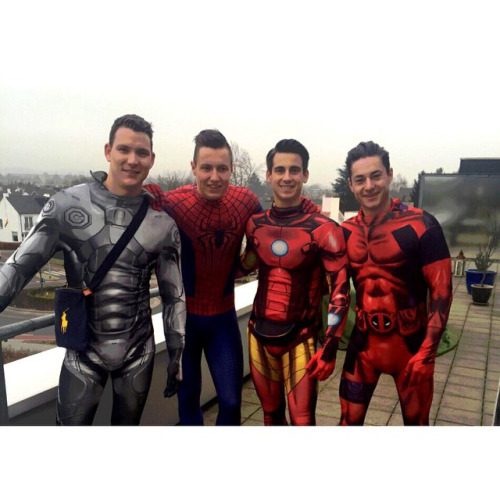 Four men wearing superhero costumes pose for a group photo on an outdoor patio.
