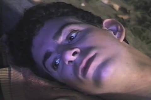 A close-up view of a young man with dark curly hair lying down under dramatic purple lighting.