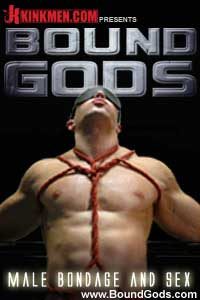 A muscular, shirtless man wearing a black blindfold is bound with red rope around his chest against a dark background.