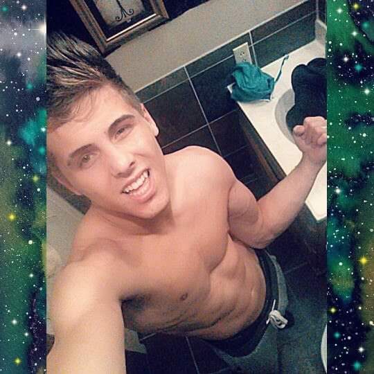 A shirtless twunk flexes his muscles for a bathroom selfie, showing off his defined abs and toned arms.