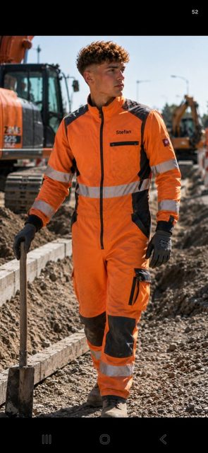 A young man in an orange construction uniform and gloves stands with a shovel at a worksite.
