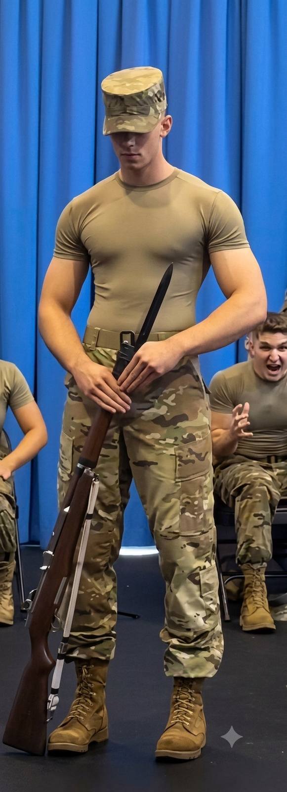 A muscular young man in a tight military t-shirt and camouflage pants poses with a rifle and bayonet.