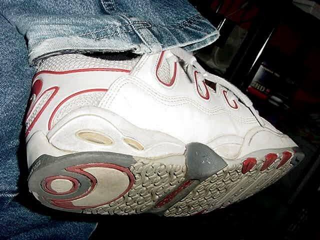 A person wears denim jeans, white sneakers, and white socks.