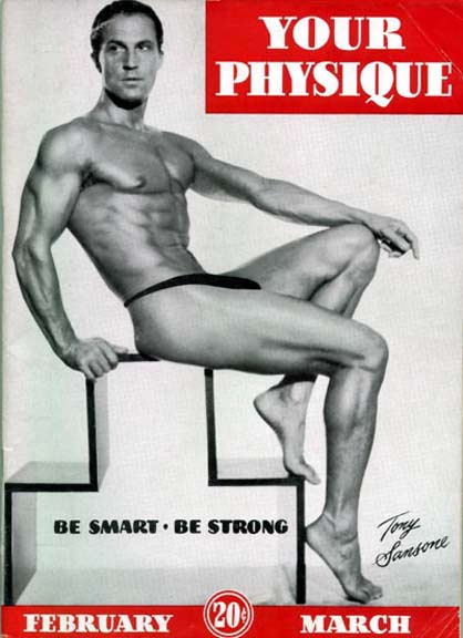 Vintage physique magazine cover featuring a muscular, smooth-skinned man in a posing strap seated on a geometric studio block.