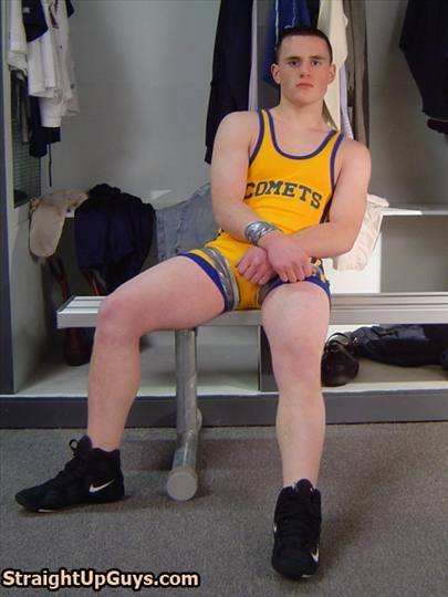 A young jock in a yellow wrestling singlet and wrestling shoes sits on a locker room bench with duct tape wrapped around his wrists and legs.